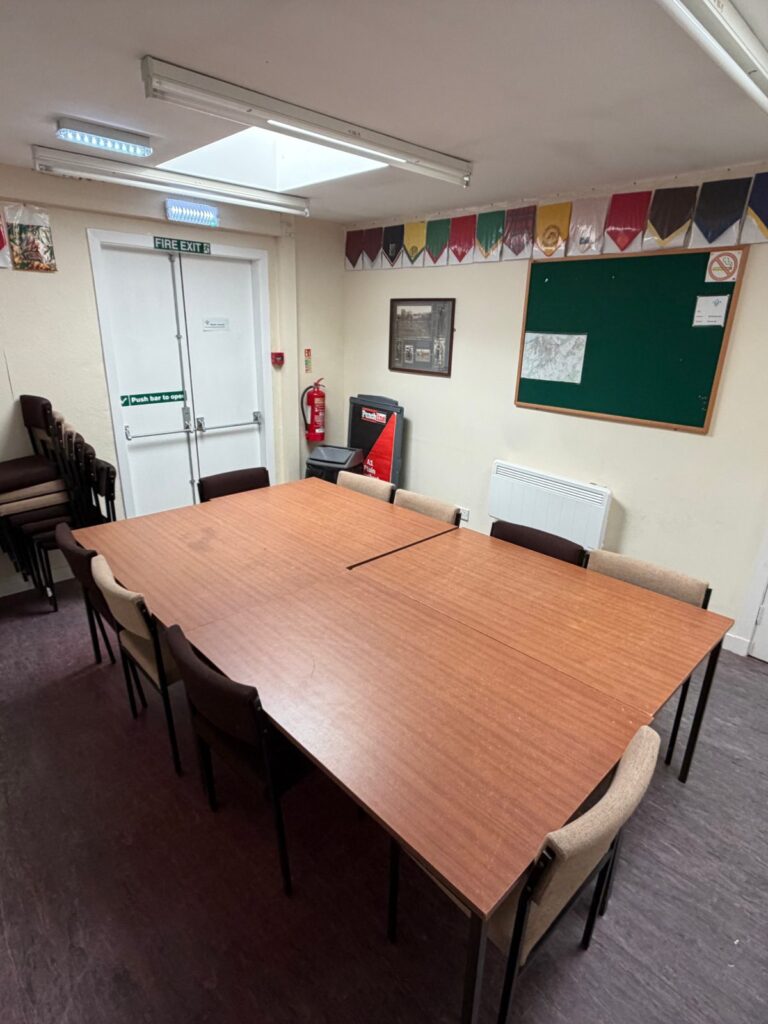 The meeting room from the corner, showing the table, the fire exit and the noticeboard.
