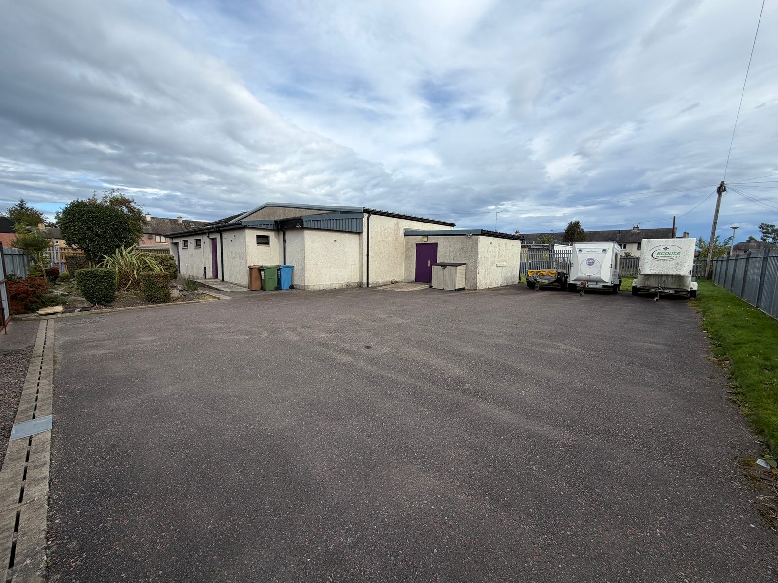 The car park at the side of Dalneigh Scout Hall, with the purple side door and the district's trailers at the far end.
